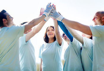 Image showing group of happy volunteers making high five in park