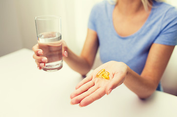 Image showing close up of woman hands with capsules and water