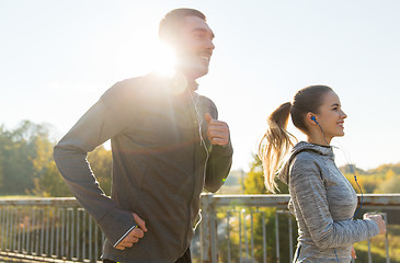 Image showing happy couple with earphones running outdoors