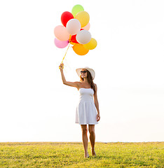 Image showing smiling young woman in sunglasses with balloons