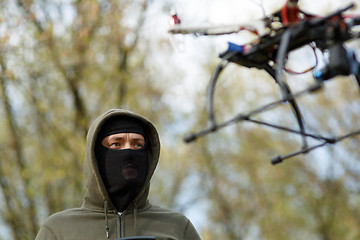 Image showing Man in mask operating a drone with remote control.