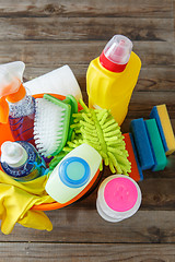 Image showing Plastic bucket with cleaning supplies on wood background