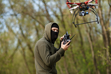 Image showing Man in mask operating a drone with remote control.