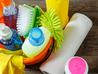 Image showing Plastic bucket with cleaning supplies on wood background