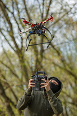 Image showing Man in mask operating a drone with remote control.