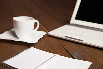 Image showing Cup of coffee,notebook and laptop on table