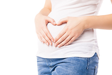 Image showing Close-up of pregnant woman embracing belly with heart shape