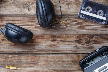 Image showing Cassette tapes, cassette player and headphones over wooden table. top view.