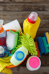 Image showing Plastic bucket with cleaning supplies on wood background