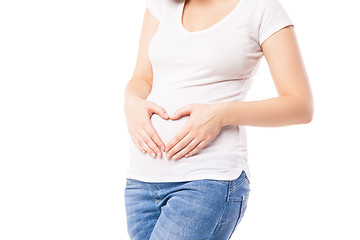 Image showing Close-up of pregnant woman embracing belly with heart shape