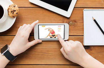 Image showing close up of woman with smartphone on wooden table