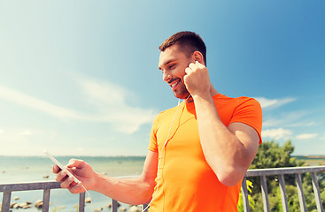 Image showing smiling young man with smartphone and earphones