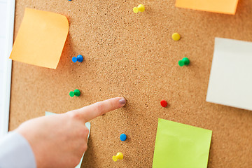 Image showing hand pointing to cork board with stickers and pins