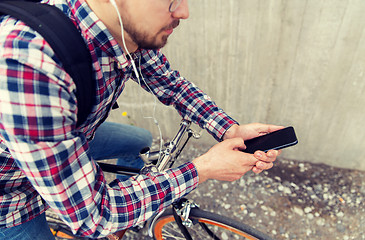 Image showing hipster man in earphones with smartphone and bike