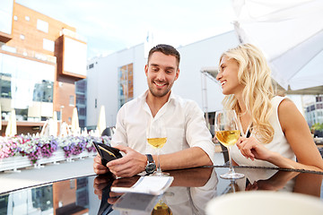 Image showing happy couple with wallet paying bill at restaurant