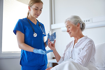 Image showing nurse giving medicine to senior woman at hospital