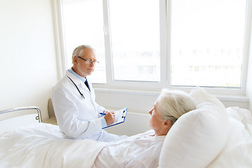 Image showing senior woman and doctor with clipboard at hospital