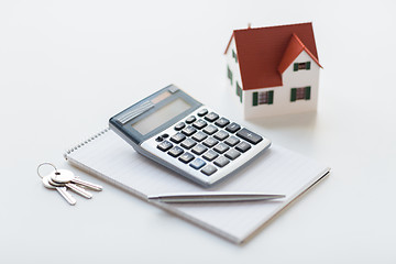 Image showing close up of home model, calculator and notebook