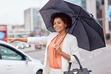 Image showing happy african woman with umbrella catching taxi