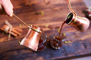 Image showing To pour arabic coffee in cups on wooden background.