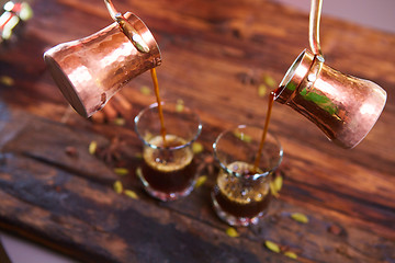 Image showing To pour arabic coffee in cups on wooden background.