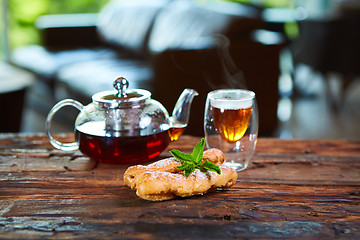 Image showing Tasty eclair and cup of tea on wooden table