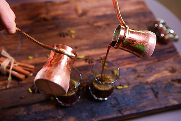 Image showing To pour arabic coffee in cups on wooden background.