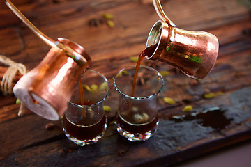 Image showing To pour arabic coffee in cups on wooden background.