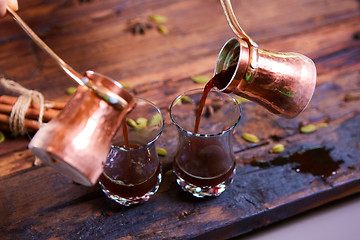 Image showing To pour arabic coffee in cups on wooden background.