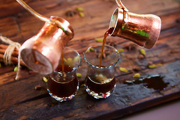 Image showing To pour arabic coffee in cups on wooden background.