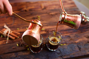 Image showing To pour arabic coffee in cups on wooden background.