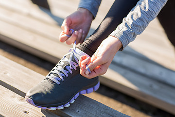 Image showing close up of sporty woman tying shoelaces outdoors