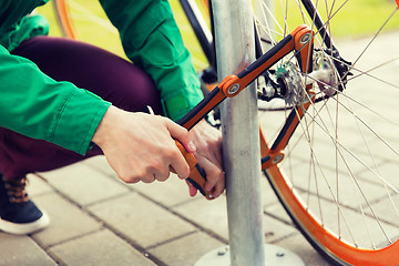 Image showing close up of man fastening bicycle lock on parking