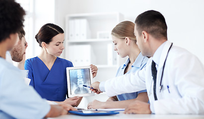 Image showing group of doctors with x-ray on tablet pc at clinic