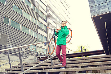 Image showing young hipster man carrying fixed gear bike in city