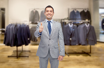 Image showing happy businessman in suit over clothing store