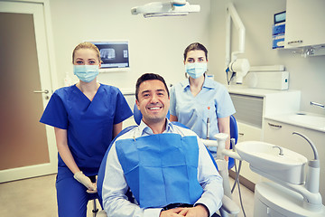 Image showing happy female dentists with man patient at clinic