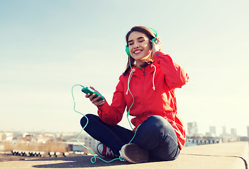 Image showing happy young woman with smartphone and headphones