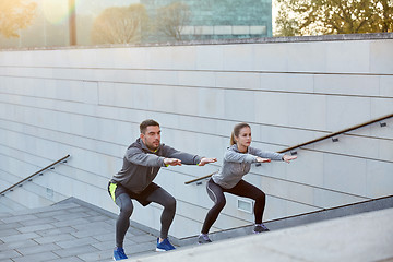 Image showing couple doing squats on city street stairs