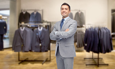 Image showing happy businessman in suit over clothing store