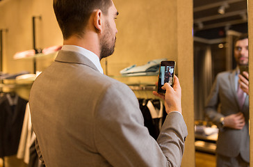 Image showing close up of man in suit taking mirror selfie