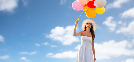 Image showing smiling young woman in sunglasses with balloons