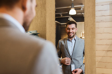 Image showing man trying jacket on at mirror in clothing store