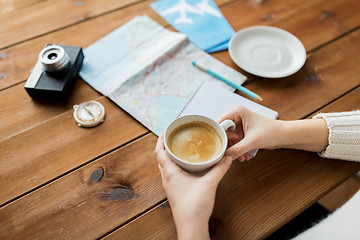 Image showing close up of hands with coffee cup and travel stuff