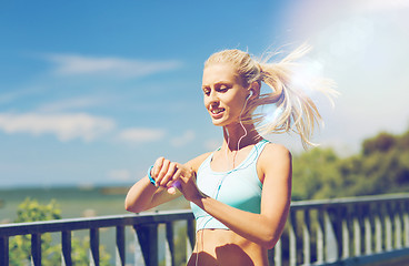 Image showing happy woman with heart rate watch and earphones