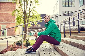 Image showing happy young hipster man sitting on stairs in city