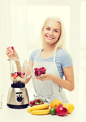 Image showing smiling woman with blender preparing shake at home