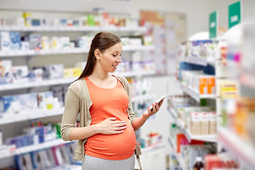 Image showing happy pregnant woman with smartphone at pharmacy