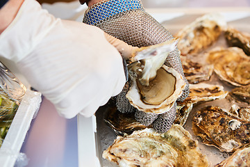 Image showing Fresh oyster held open with knife in hand