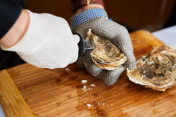 Image showing Fresh oyster held open with knife in hand